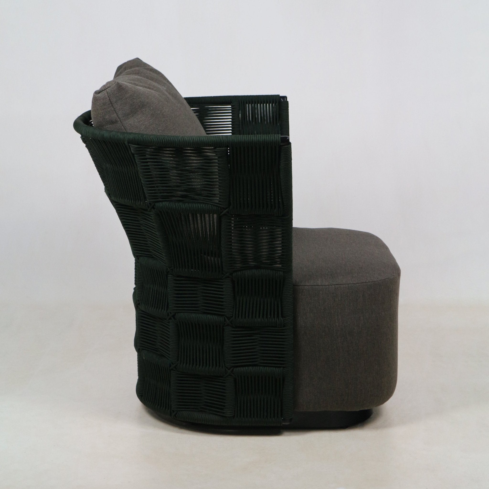 Side view of a coastal modern outdoor accent chair with a dark green woven rope back and gray fabric-upholstered seat and matching back cushion on a low rounded base.