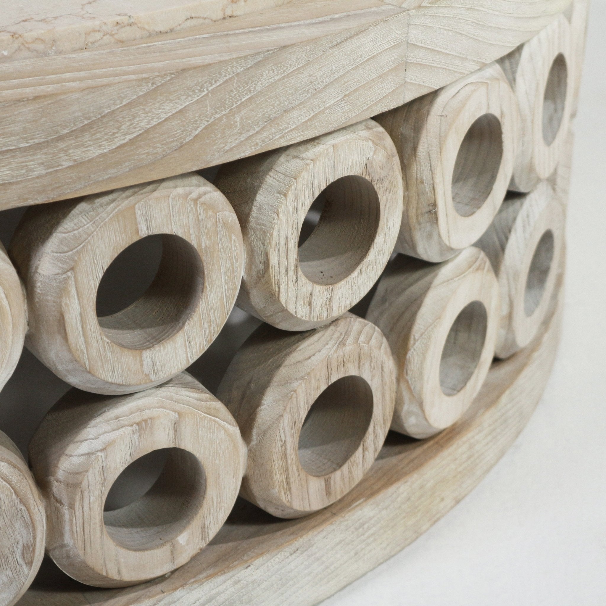 Close-up of a natural oak coffee table base featuring stacked hollow circular wooden rings with visible grain and a light travertine tabletop edge.