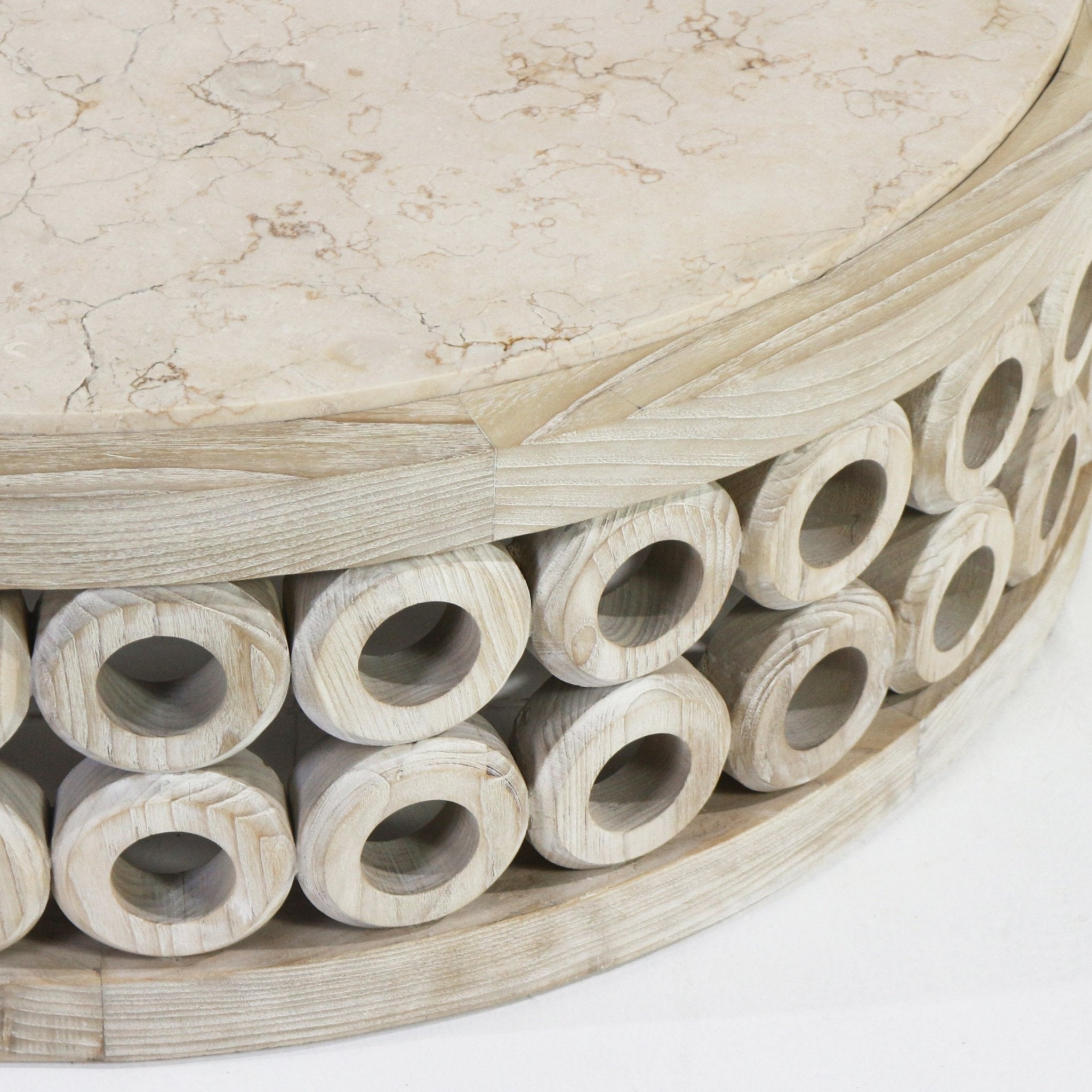 Close-up of a round natural travertine tabletop resting on a light oak coffee table base made from stacked hollow oak rings in a modern, contemporary style.