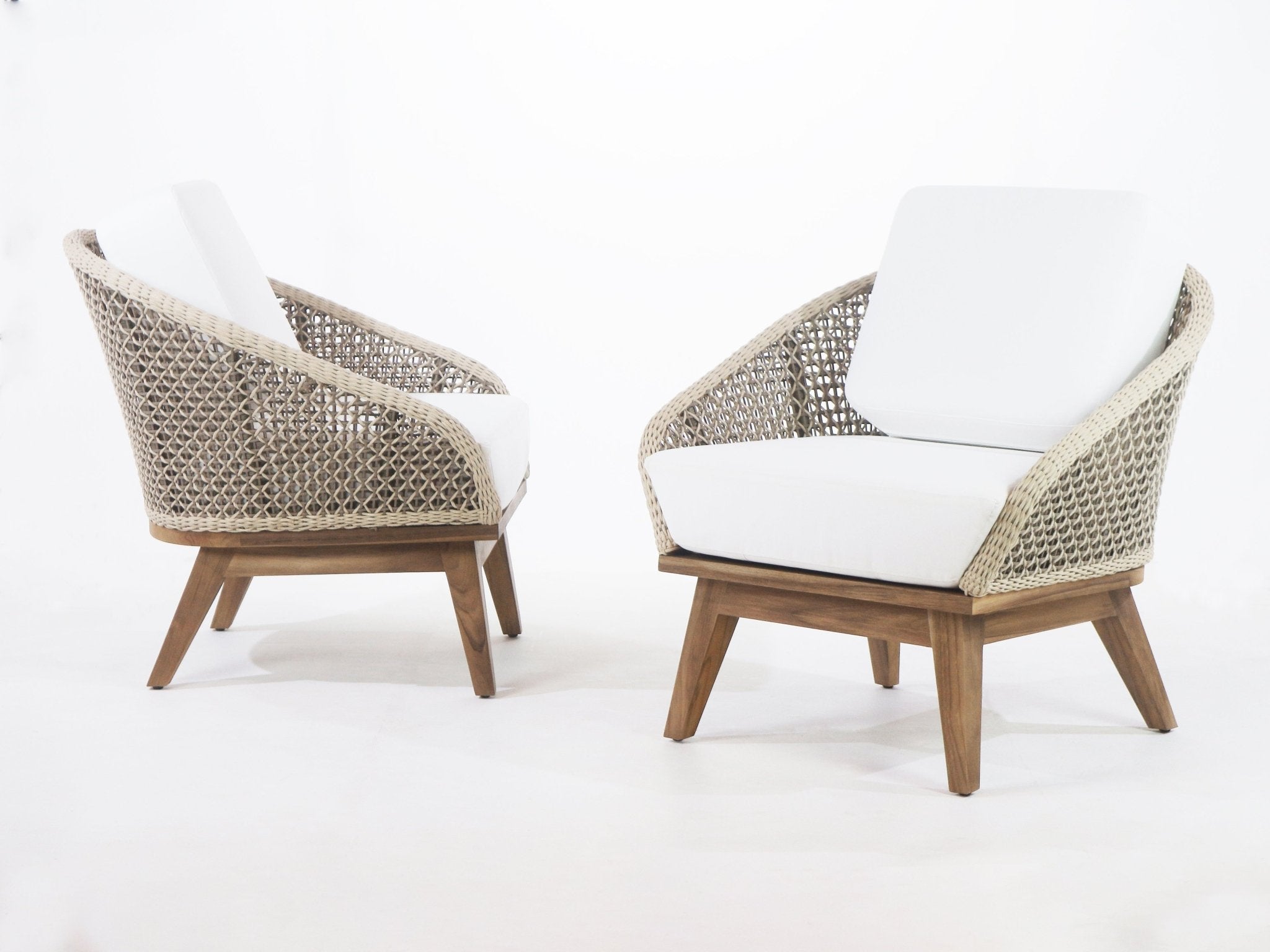 Two coastal-style outdoor accent chairs with beige rope-woven backs, white fabric cushions, and tapered teak wood bases shown on a white background, angled to display front and side profiles.