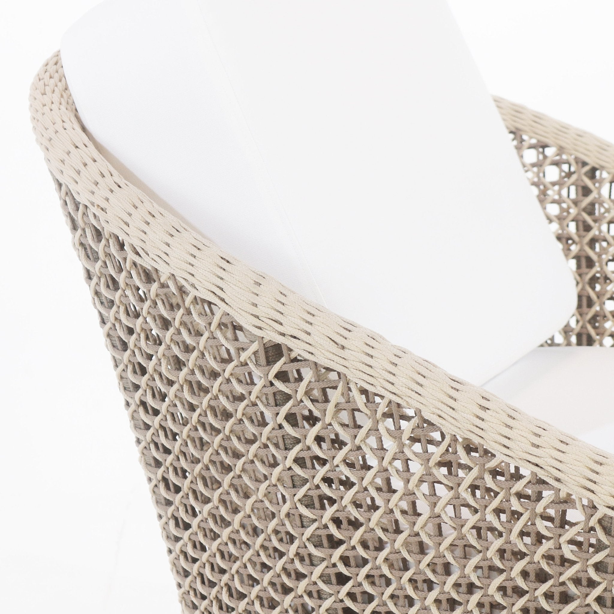 Close-up of a beige rope-woven outdoor accent chair arm and back with a white fabric cushion, highlighting the woven pattern and cushioned seat.