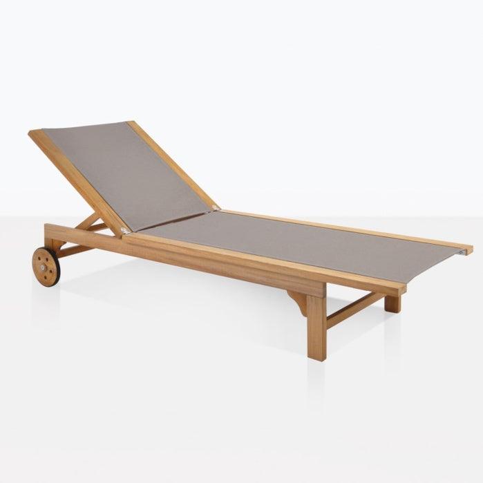 Teak outdoor sun lounger with a natural wood frame and taupe fabric sling, adjustable backrest and wooden rear wheels for easy repositioning—coastal contemporary design for patio or garden.