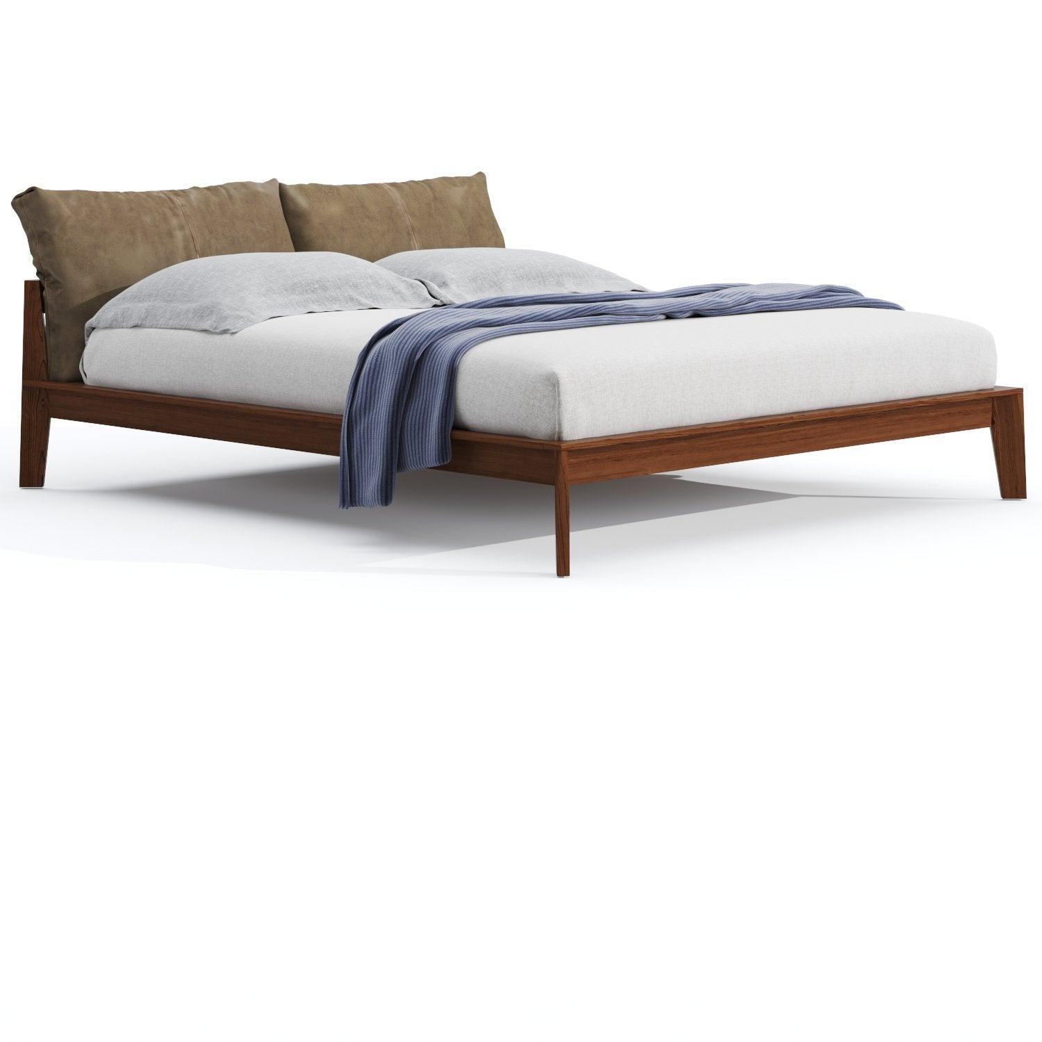 Mid-century modern king-size teak platform bed with low-profile solid teak frame and tapered legs, styled with light gray bedding, two oversized brown suede back cushions and a blue knit throw draped across the foot.