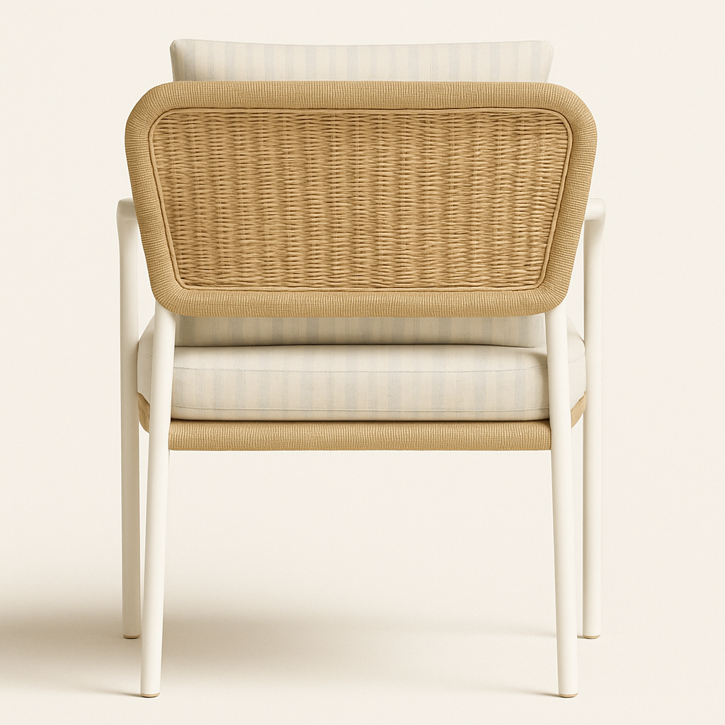 Back view of a coastal outdoor accent chair with a white aluminum frame, woven natural wicker back panel and a light blue-and-white striped seat cushion and back pillow.
