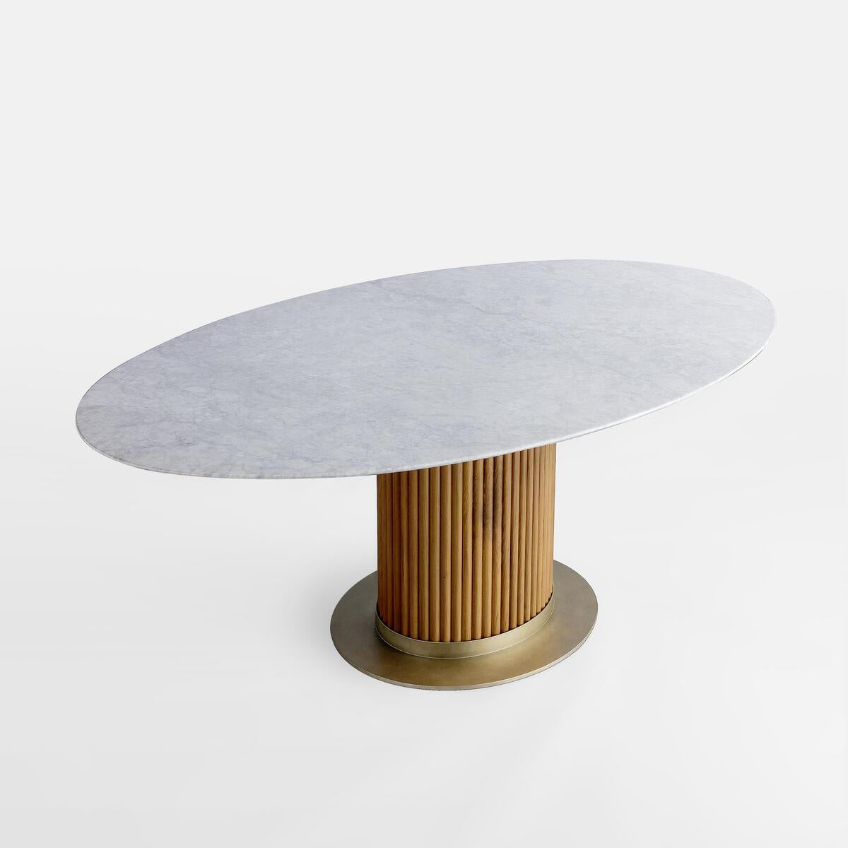 Oval white marble dining tabletop paired with a fluted oak cylindrical pedestal and round brass metal base, shown on a plain white background.