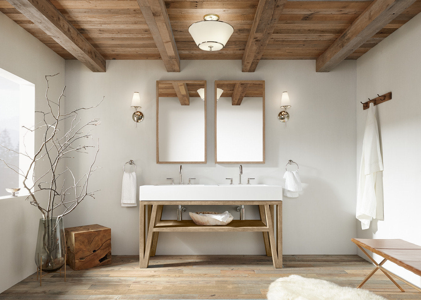 Contemporary freestanding double-sink vanity in light natural solid wood with a white integrated rectangular stone top, two chrome faucets, matching wood-framed mirrors, brass wall sconces and open lower shelving.