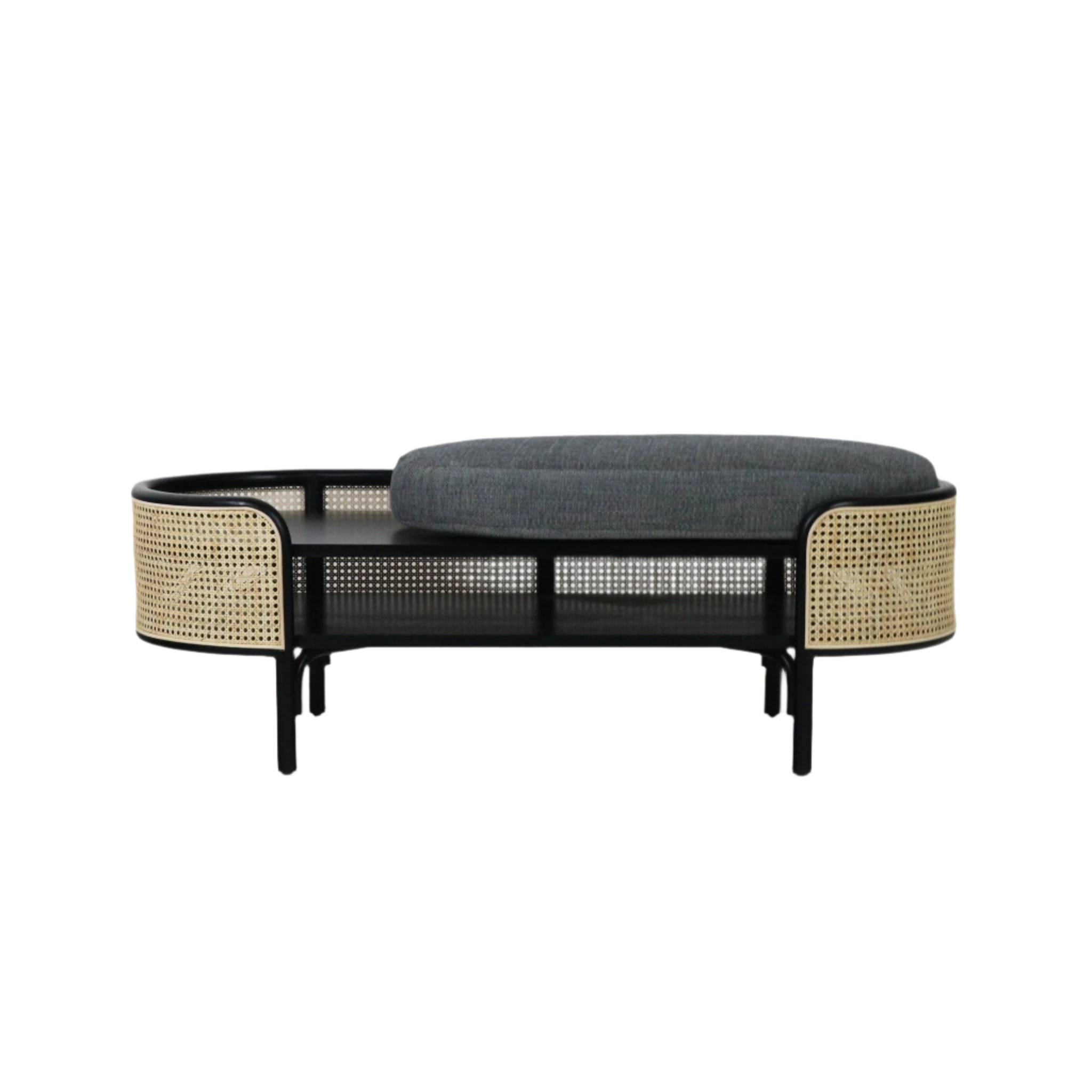 Boho modern armless bench with a black solid-wood frame, woven rattan cane side panels, lower shelf and a gray upholstered fabric cushion.