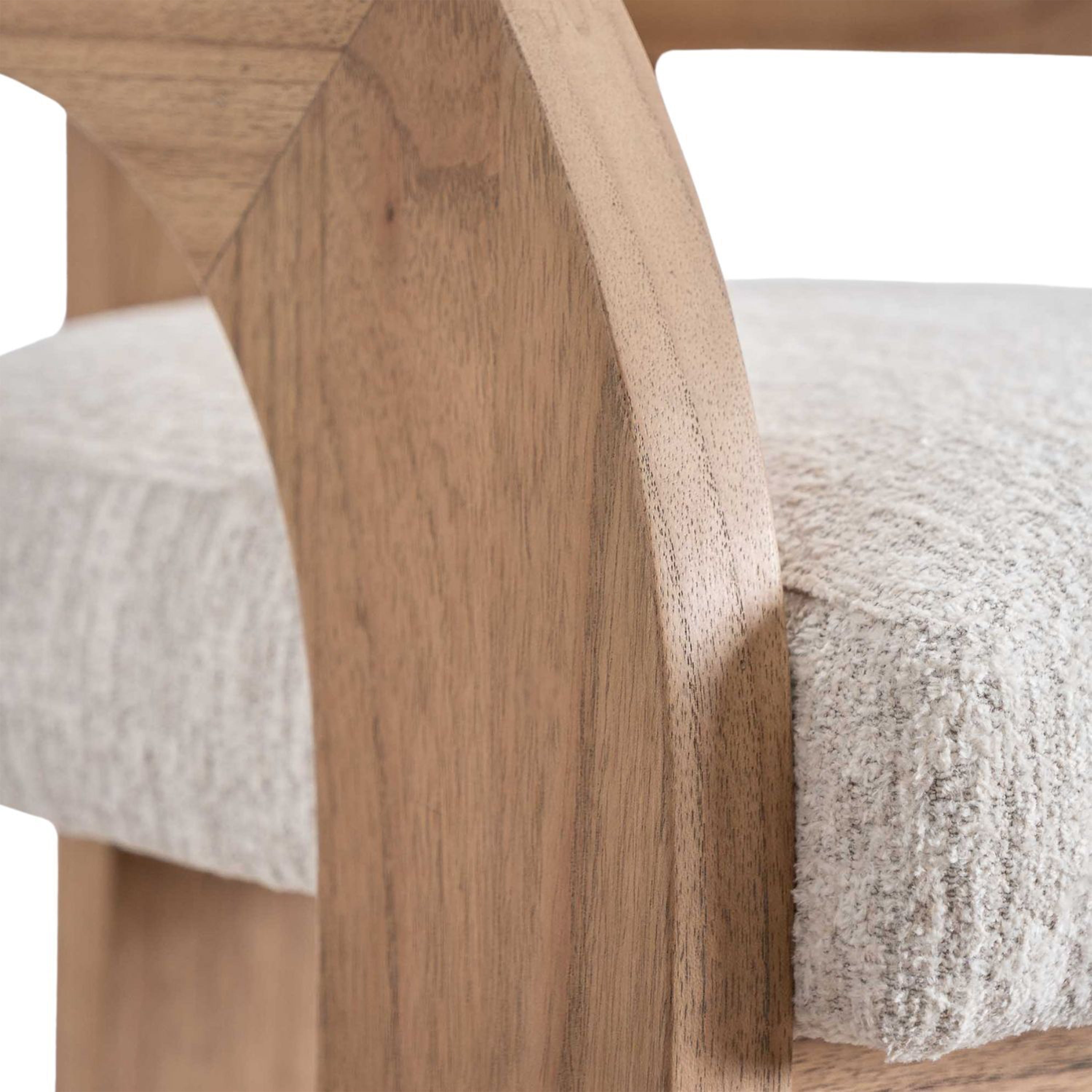 Close-up of a light natural wood U-shaped armrest and the edge of a cream textured fabric seat on a modern upholstered bar counter stool.