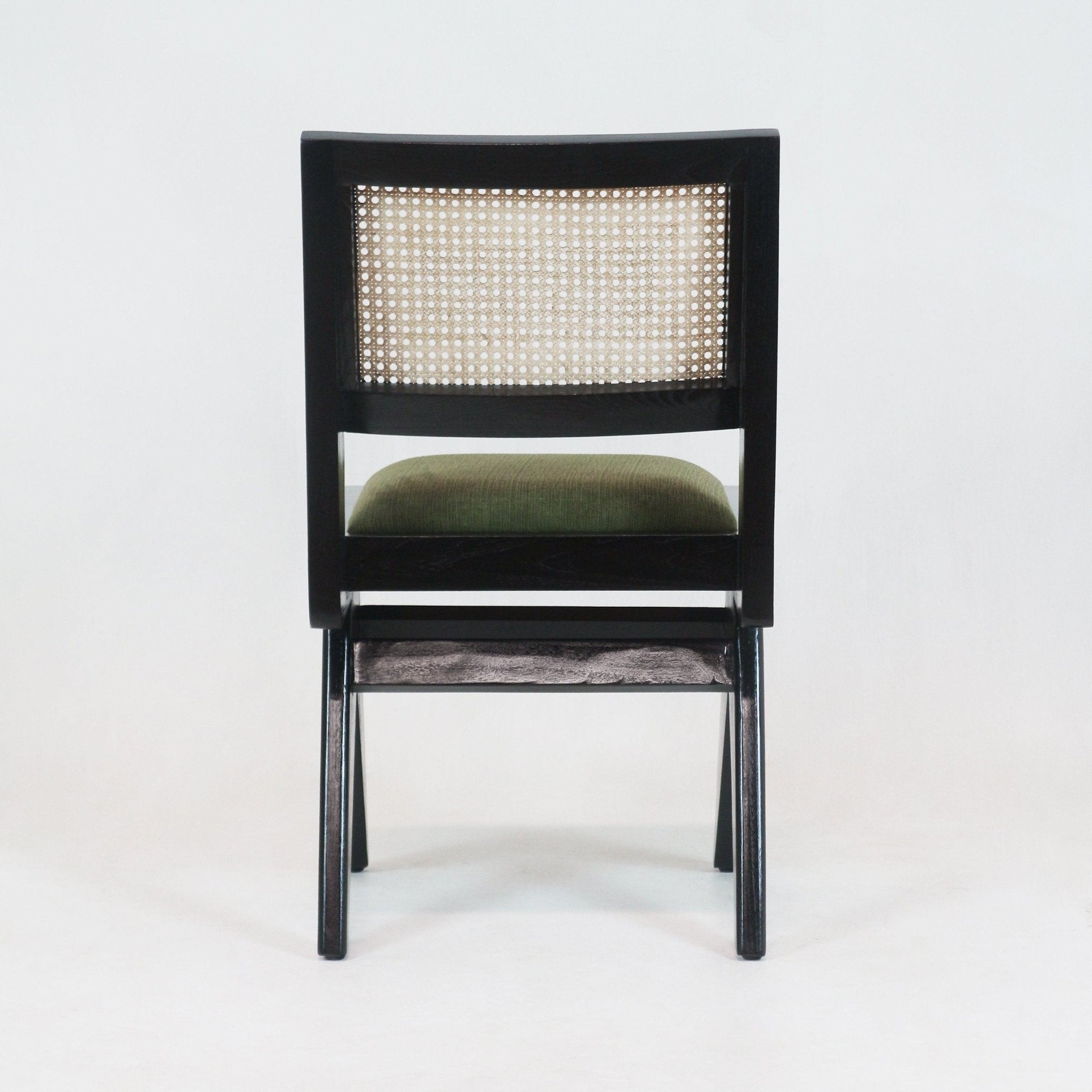 Rear view of a modern black solid wood dining chair with a natural woven cane back panel and green upholstered seat cushion, armless frame shown on a white background.