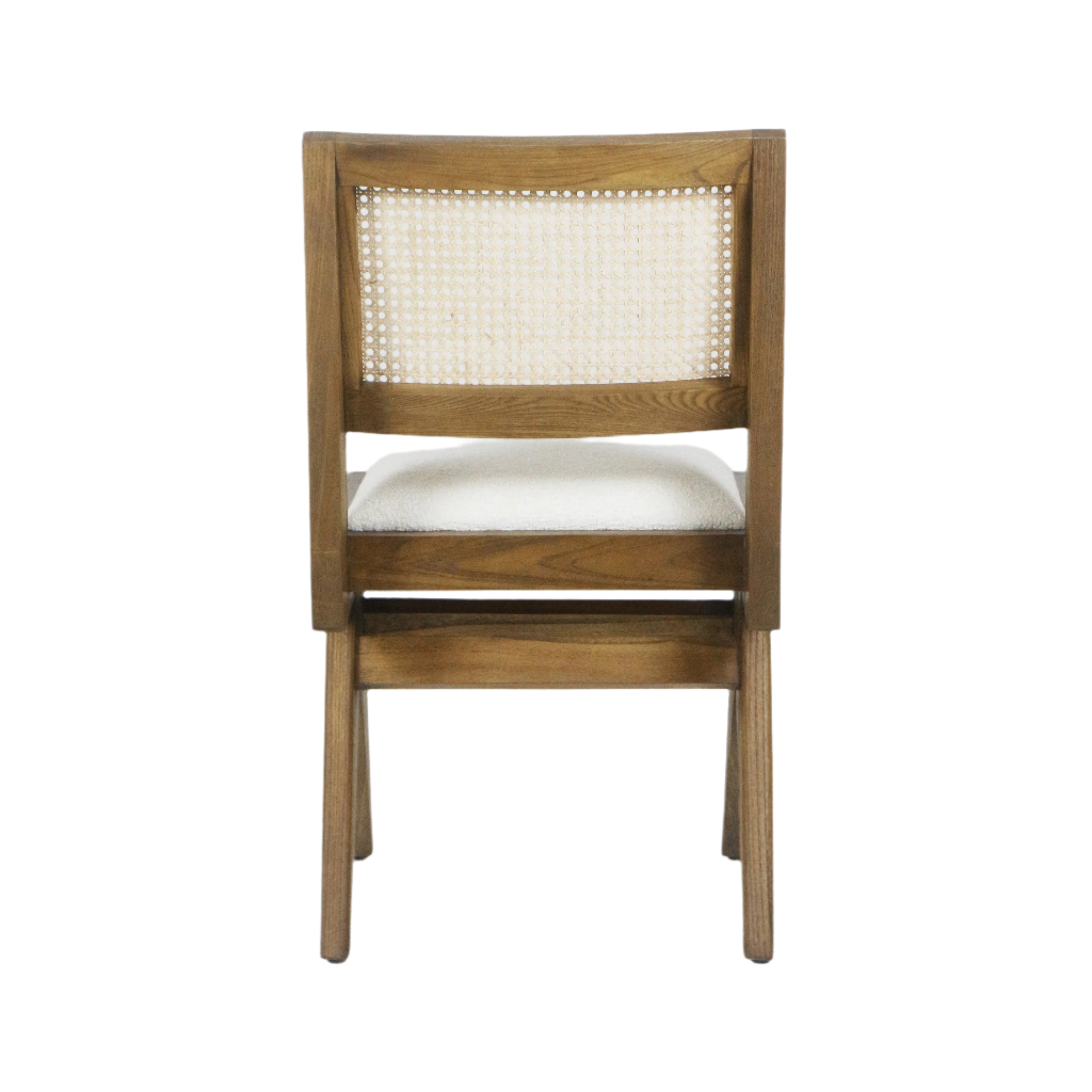 Rear view of an armless dining chair with a natural ash wood frame, woven cane back panel and a cream boucle upholstered seat cushion on tapered wooden legs.