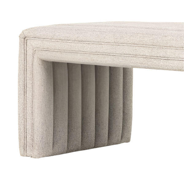 Close-up of a natural beige boucle fabric end-of-bed bench corner, showing the cushioned top and vertically channel-tufted upholstered leg in a modern coastal style.