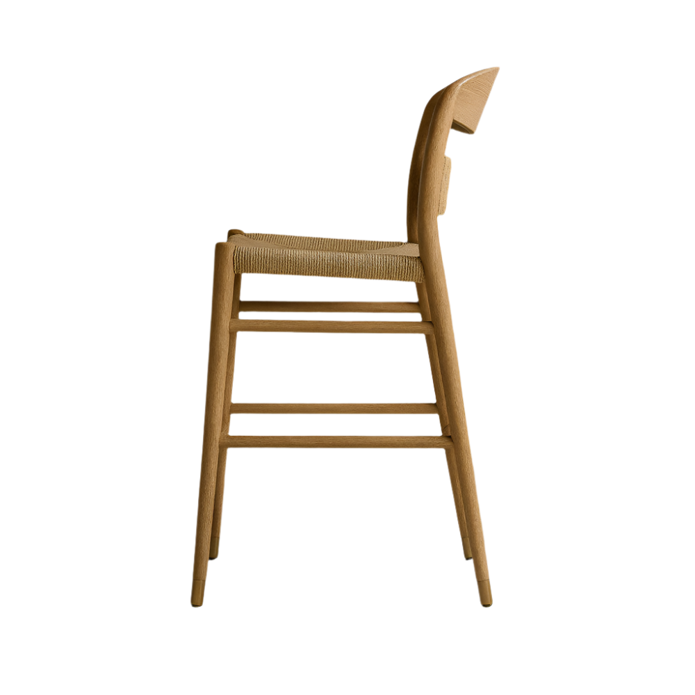 Side profile of a mid-century modern natural wood bar stool with a woven papercord seat, gently curved low back, tapered legs and horizontal stretchers on a white background.