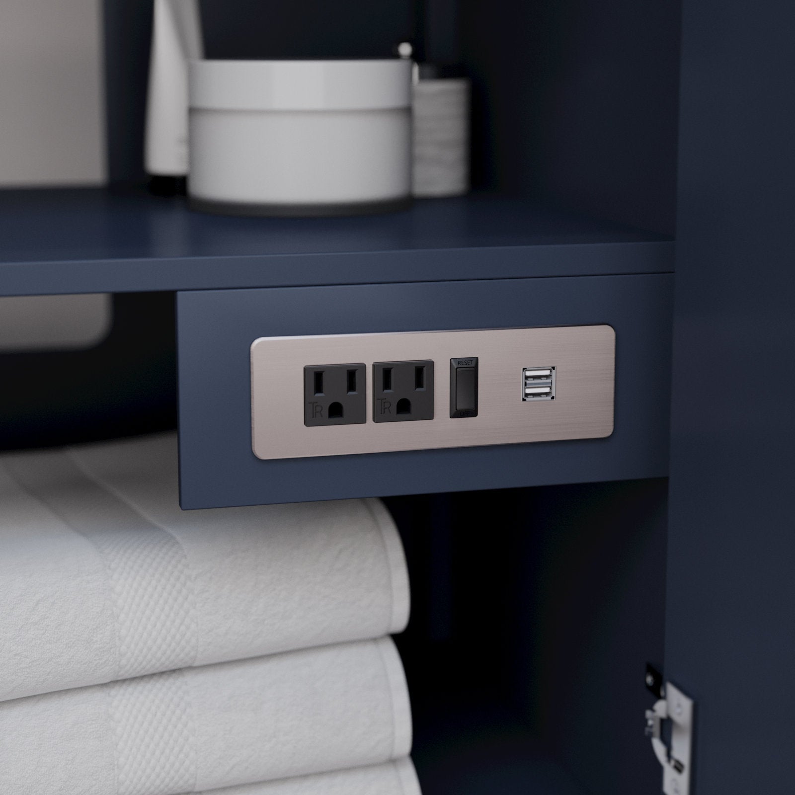 Close-up of a brushed nickel outlet plate recessed into a stone-finish solid wood modern bathroom vanity, showing two power sockets, a reset switch and dual USB ports above neatly folded white towels.