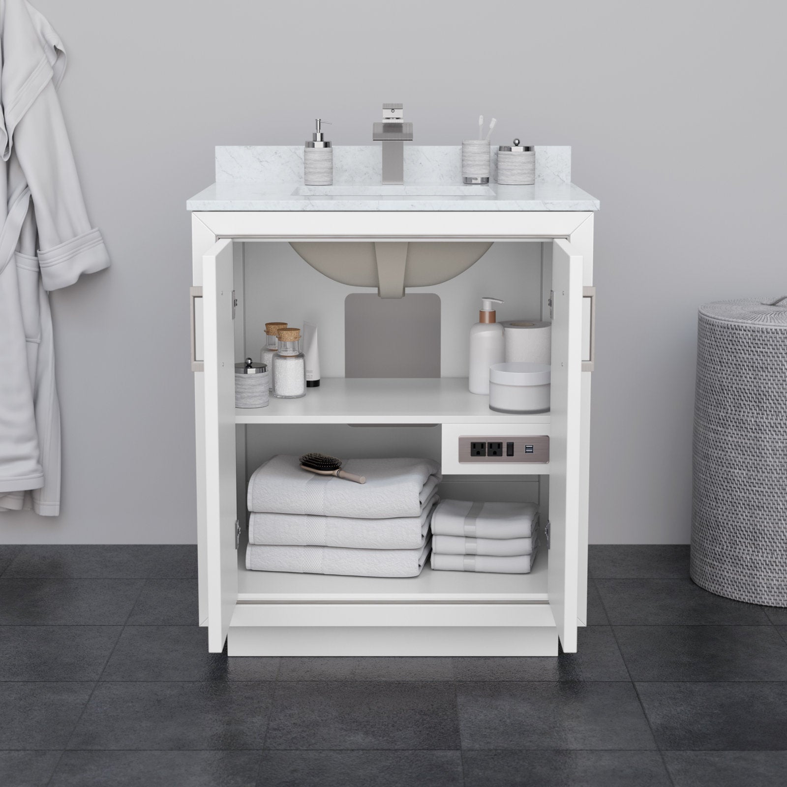 Front view of a 30-inch modern white solid wood bathroom vanity with a light stone countertop and integrated sink; open cabinet doors reveal shelves with folded white towels, toiletries, a hairbrush and a built-in power outlet.
