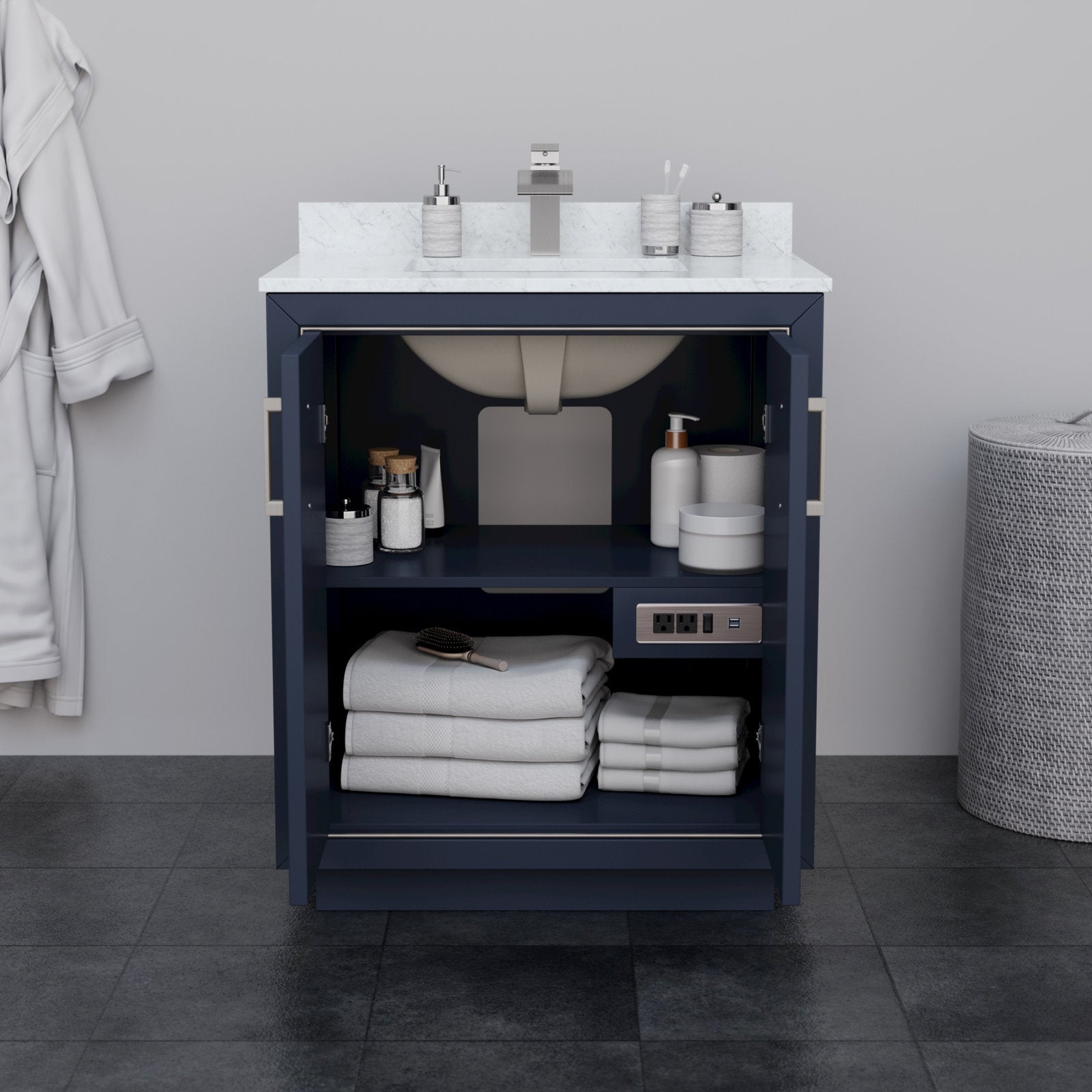 Open 30-inch modern solid wood bathroom vanity with stone countertop and integrated ceramic sink, navy base with open doors showing shelf storage of folded towels, toiletries and built-in power outlets.